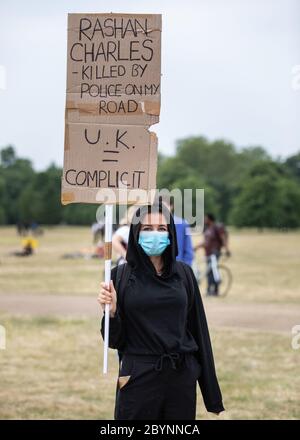 Londra, Regno Unito. 3 Giugno 2020. Migliaia di persone protestano ad Hyde Park in solidarietà con Black Lives contano. Una donna protetaria che indossa una maschera porta un bannerdenuncia l'uccisione di Rashan Charles da parte della polizia. Gli Stati Uniti sono stati scosso da giorni di protesta in molte città, dopo che George Floyd, un uomo nero, è morto nella custodia della polizia il 25 maggio a Minneapolis. Credit Carol Moir/Alamy News Foto Stock