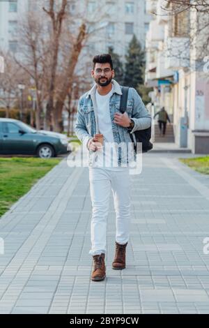 Un uomo indiano con un'elegante bearded che beve caffè da asporto sulla strada. Foto Stock