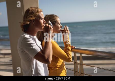 Coppia caucasica bere caffè su un balcone durante la quarantena per coronavirus Covid19 padella Foto Stock