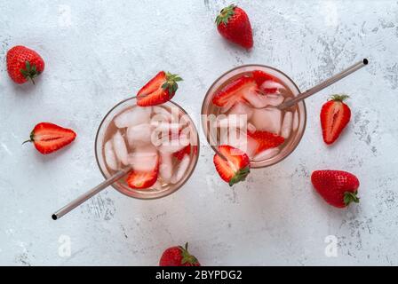 Due cocktail di fragole con ghiaccio su sfondo chiaro con frutti di bosco. Vista dall'alto Foto Stock