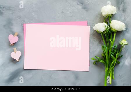 Fock up del biglietto di auguri. Carta rosa vuota con fiori e cuori. Composizione piatta. Vista dall'alto con spazio per la copia Foto Stock