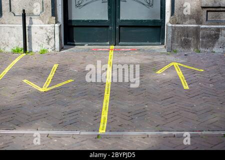 Ingresso ad un pub con nastro adesivo giallo che ricorda alle persone in olandese di mantenere la distanza sociale di 1,5 metri e in quale direzione entrare e uscire Foto Stock