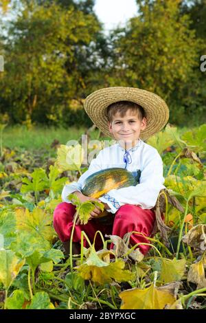 Ragazzo sorridente che tiene in mano una grande zucca gialla Foto Stock