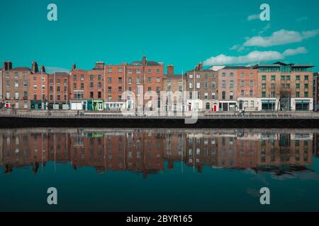 Dublino / Irlanda : gli edifici si riflettono in una calma acque del fiume Liffey lungo Ormond Quay a Dublino durante una giornata di primavera irlandese molto soleggiata Foto Stock