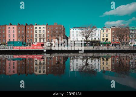 Dublino / Irlanda : gli edifici si riflettono in una calma acque del fiume Liffey lungo Ormond Quay a Dublino durante una giornata di primavera irlandese molto soleggiata Foto Stock