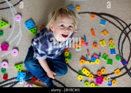 Bambino piccolo biondo, ragazzo che gioca con i giocattoli di legno che sviluppa e che impara le attività Foto Stock