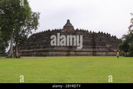 BOROBUDUR, INDONESIA - 10 giugno 2013: Visitatori al tempio di Borobudur. Vista panoramica completa dalla base del tempio. Candi Borobudur è la più grande temperatura buddista Foto Stock