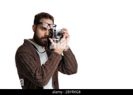 Fotografo esperto con fotocamera su una cinghia isolata su sfondo bianco. Modello con pullover marrone caldo e ha un bel nero Foto Stock