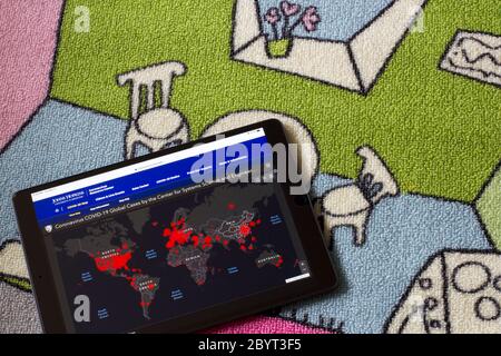 Un iPad sulla moquette della camera da letto dei bambini che mostra una mappa live dei casi globali COVID-19 confermati, creati da ricercatori del CSSE presso la Johns Hopkins University. Foto Stock