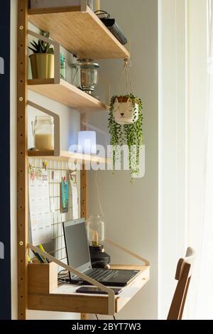 Piccola stazione remota per ufficio domestico, con computer portatile, piante domestiche, lavagna metallica, candele e lampada da tavolo. Shot verticale. Foto Stock