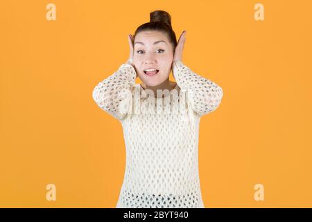 la ragazza copre le orecchie con le mani, non volendo ascoltare nulla, guarda la fotocamera. Foto Stock