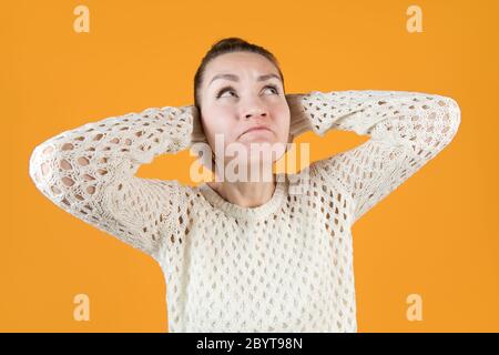 La giovane donna copre le orecchie strettamente e guarda in su anggria. Grandangolo Foto Stock