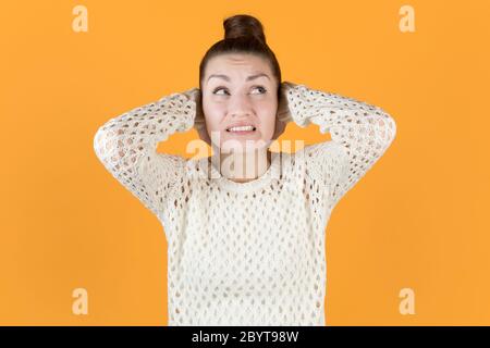 La giovane donna copre le orecchie strettamente e guarda in su Foto Stock