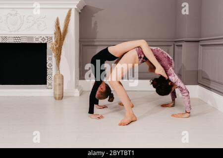 La sorella maggiore insegna yoga alla sorella più giovane in un bellissimo interno Foto Stock