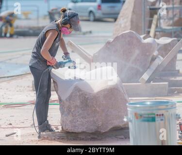 Un artista lavora su un grande blocco di pietra alla scultura di San Giovanni, un simposio di scultura che ospita artisti di tutto il mondo. Foto Stock