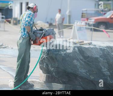 Un artista lavora su un grande blocco di pietra alla scultura di San Giovanni, un simposio di scultura che ospita artisti di tutto il mondo. Foto Stock