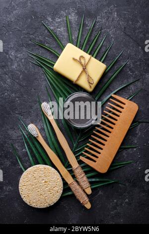 Spazzole dentali in bambù naturale, polvere dentale nera, pettine per capelli, sapone e spugna su sfondo grigio scuro, prodotti senza scarti, igiene orale naturale, copia Foto Stock