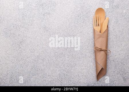 Stoviglie di bambù a zero rifiuti, tovaglioli e tazze eco-compatibili, posate in legno su sfondo naturale in pietra. Spazio di copia vista dall'alto Foto Stock