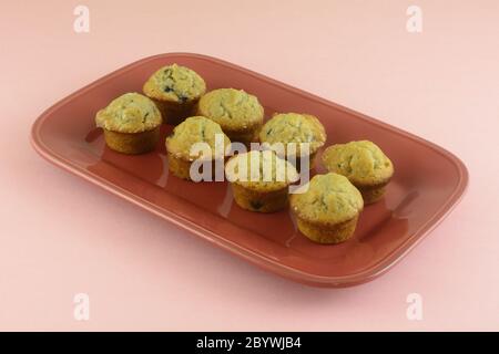 Mini muffin ai mirtilli su piastra per brunch rossa su sfondo rosa Foto Stock