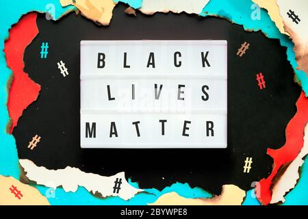 Movimento BLM. Foro di carta con bordi bruciati, testo Black Lives materia su scatola luminosa, hashtag intorno. Protesta, dimostrazione, movimento contro il razzismo, rac Foto Stock