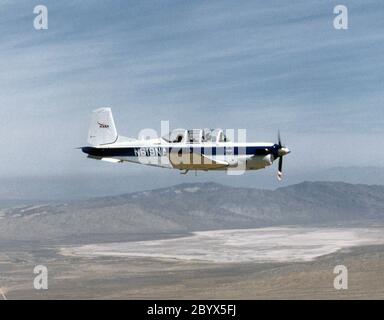 Un aereo della NASA T-34C, utilizzato per inseguimento di sicurezza, è mostrato volare sopra il Dryden Flight Research Center, Edwards, California nel marzo 1997. L'aeromobile era precedentemente utilizzato presso il Lewis Research Center in esperimenti di propulsione che coinvolgevano motori turboelica, ed era utilizzato come velivolo di inseguimento a Dryden per progetti di ricerca più piccoli e lenti. Chase Aircraft accompagna i voli di ricerca per scopi fotografici e video, nonché come supporto per la sicurezza e la ricerca. A Dryden, il T-34 è utilizzato principalmente per veicoli pilotati a distanza più piccoli che volano più lentamente rispetto al F-18 della NASA, utilizzato per i proj su larga scala Foto Stock