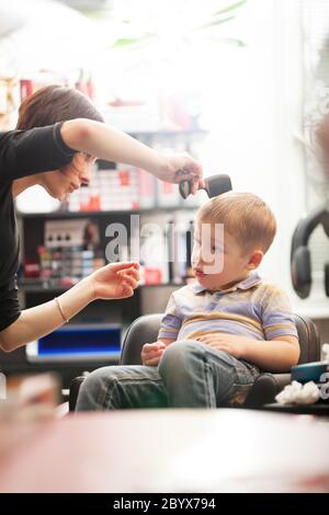 Ragazzo piccolo che ha un taglio di capelli in un salone Foto Stock