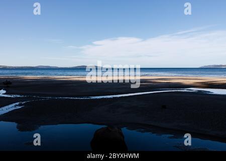 Bella spiaggia incontaminata Tasmanina con insenature d'acqua e con sereno cielo blu in una mattina d'inverno Foto Stock