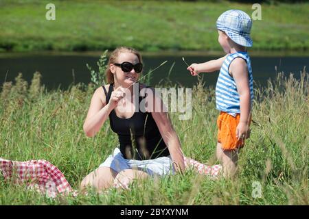 Madre e figlio giocano con l'erba sul prato Foto Stock