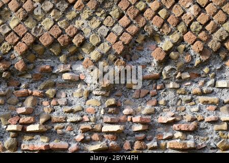 Primo piano storico antica tecnica di costruzione in muratura romana, chiamata Opus reticulatum, con una struttura in pietra parzialmente danneggiata. Foto Stock