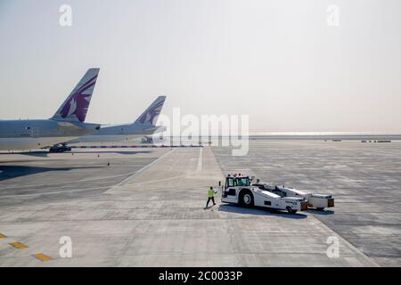 Equipaggio di terra sul asfalto presso un aeroporto internazionale di Doha quasi desertato durante il blocco causato dal virus COVID-19. In tutto il mondo, il settore del traffico aereo è fortemente influenzato dal massiccio calo del traffico. Foto Stock