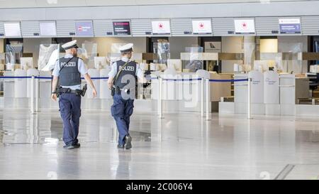 La polizia dell'aeroporto ha pattugliato l'area di check-in presso l'aeroporto di Francoforte quasi vuoto durante il blocco causato dal virus COVID-19. In tutto il mondo, il settore del traffico aereo è fortemente influenzato dal massiccio calo del traffico. Foto Stock