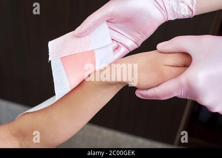 Estetista rimuove i capelli dalle mani dei woman con cera a casa Foto Stock