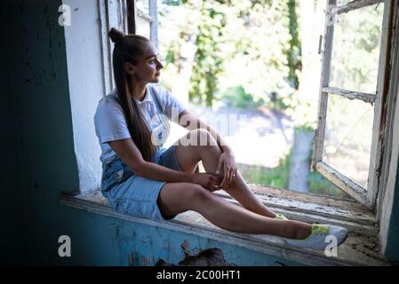 La ragazza è triste nella casa in rovina Foto Stock