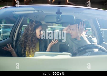 Giovane uomo e donna che smistano i rapporti in un'automobile Foto Stock