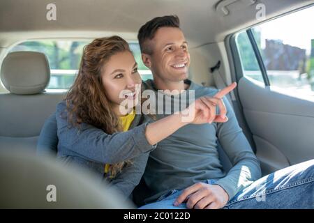 Donna che mostra mano fuori finestra e abbracciando il suo uomo in auto Foto Stock