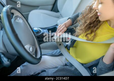 Donna concentrata nel sedile conducente nella nuova cintura di sicurezza con allacciamento per auto Foto Stock