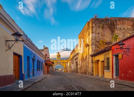 Paesaggio urbano dell'arco di Santa Catalina nel centro storico di Antigua all'alba con il vulcano Agua, Guatemala. Foto Stock