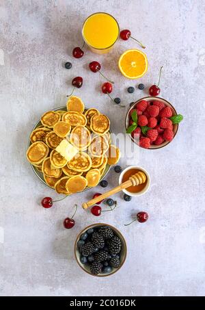 Mini pancake con miele, frutti di bosco e succo d'arancia. Foto Stock
