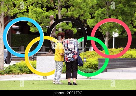 Tokyo, Giappone. 11 Giugno 2020. Le donne scattano foto degli anelli olimpici, esposti prima del nuovo stadio nazionale giapponese a Tokyo giovedì 11 giugno 2020. Il Comitato organizzatore delle Olimpiadi di Tokyo e il Comitato Olimpico Internazionale (CIO) hanno convenuto che il prossimo anno avrebbero semplificato i giochi olimpici per garantire la sicurezza del nuovo coronavirus. Credit: Yoshio Tsunoda/AFLO/Alamy Live News Foto Stock