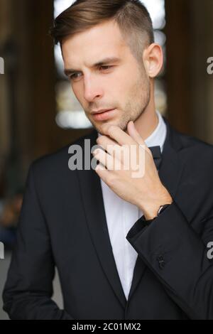 Ritratto di giovane uomo che indossa un abito nero con cravatta ad arco. Foto Stock