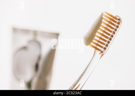 spazzolino da denti in plastica, dentifricio su sfondo bianco sfocato. Foto Stock