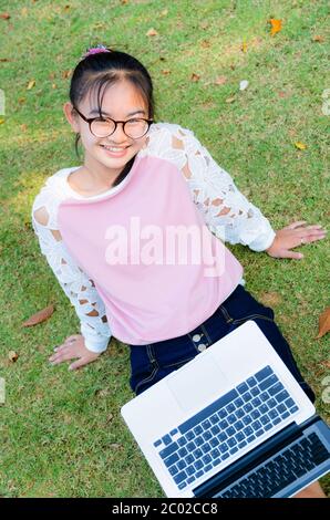 Ragazza carina è felice con notebook su erba Foto Stock