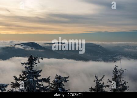 Colline di Smrk, Knehyne e Radhost dalla collina di Lysa hora in inverno Moravskoslezske Beskydy montagne nella repubblica Ceca con nebbia sulle altitudini più basse e blu Foto Stock