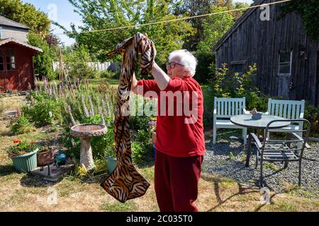 donna di 90 anni che vive da sola appesa fuori lavando ad asciugare Foto Stock