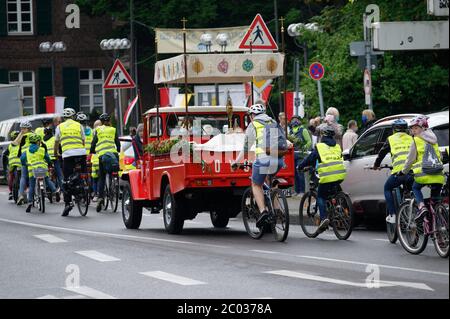 Colonia, Germania. 11 Giugno 2020. Un vecchio camion pick-up della vigna del fuoco, accompagnato da alacari ragazzi in bicicletta, trasporta la mostruosità della comunità cattolica di Colonia-Porz attraverso le strade. Invece della tradizionale processione del Corpus Domini, dovuta alla pandemia di Corona, la mostruosità, il Santissimo Sacramento, è guidata dal Corpus Domini mobile verso dodici diverse stazioni, dove in ogni caso viene celebrato un breve servizio. Credit: Henning Kaiser/dpa/Alamy Live News Foto Stock