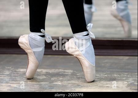 Vista ravvicinata alle ballerine gambe in pointes sul pavimento in legno Foto Stock