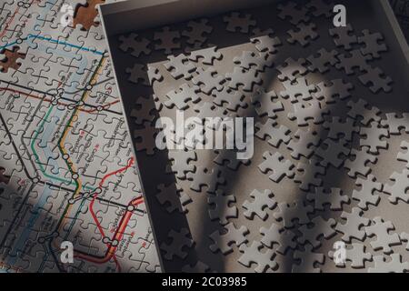 Londra, UK - 18 maggio 2020: Scatola con pezzi di puzzle bianchi in cima al puzzle con iconica mappa metropolitana di Londra moderna, progettato nel 1931 da Henry Foto Stock