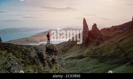 Vista posteriore del turista con zaino che sale in collina esplorando l'ambiente naturale. Una delle meraviglie più fotografate al mondo. Scozia Foto Stock