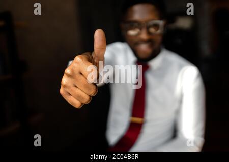 L'uomo d'affari si allungò in avanti la sua mano gesticulating classe sollevando il pollice Foto Stock