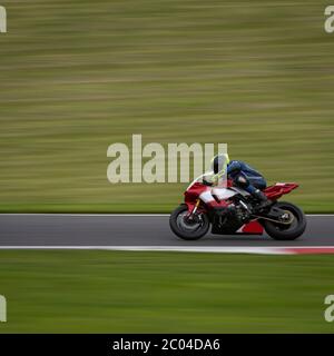 Un'inquadratura panoramica di una moto da corsa che si curva su una pista. Foto Stock